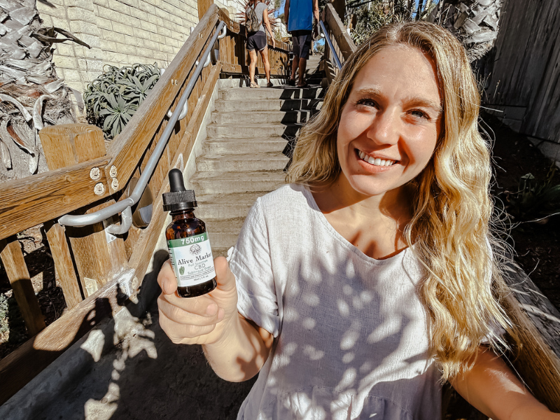 a smiling woman holding a CBD oil.