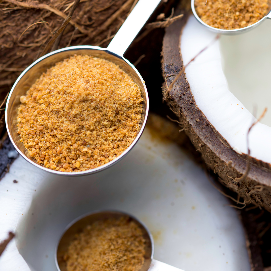 an image of a coconut split open and a spoon of sugar.